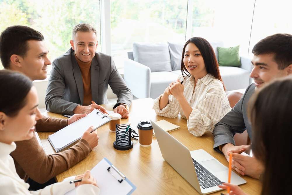Team of ecommerce marketing company professionals collaborating around a table, showcasing expertise in ecommerce development and SEO.